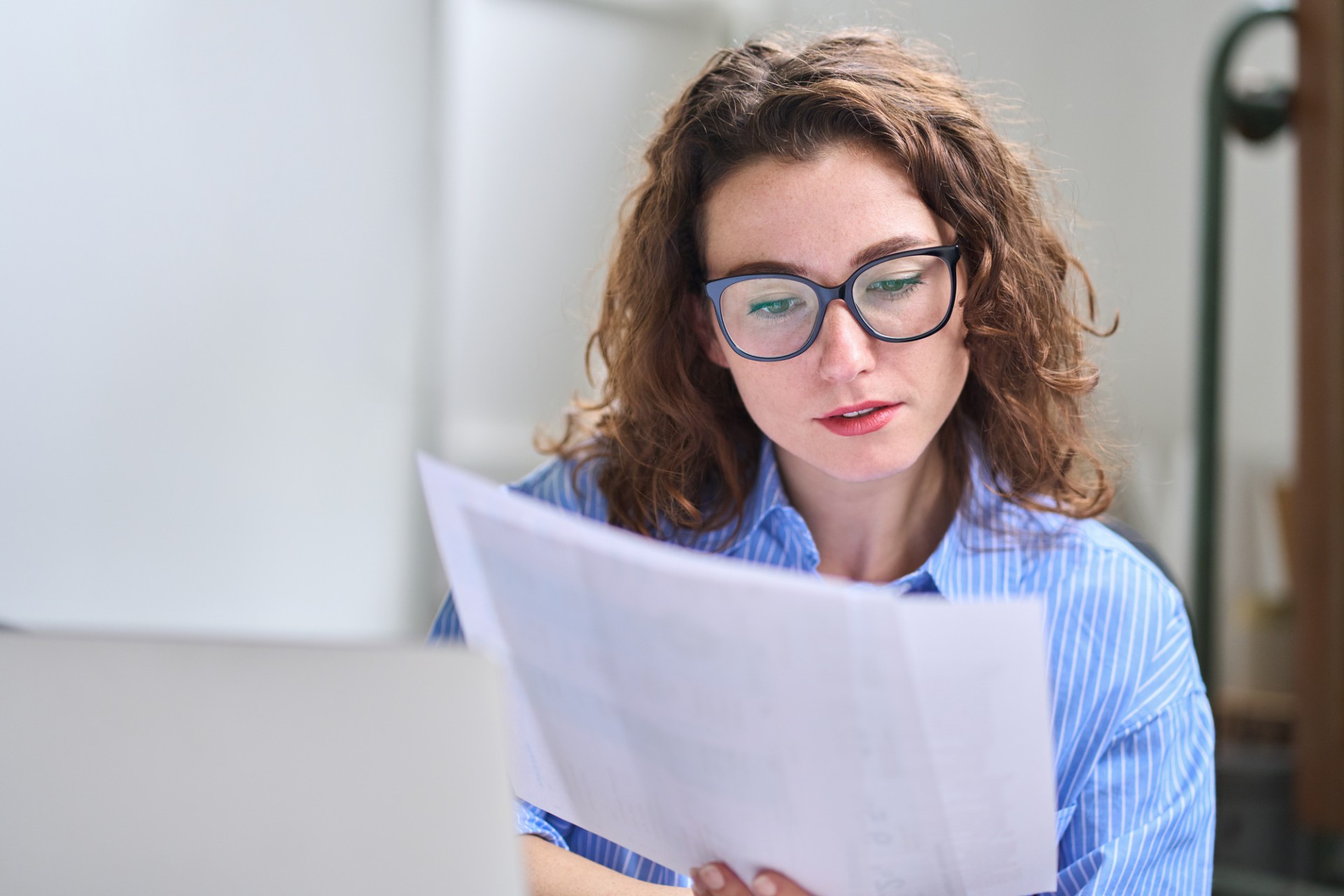 Young business woman accountant holding documents working in office.